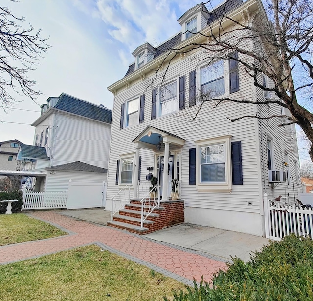 view of front of home featuring fence and mansard roof