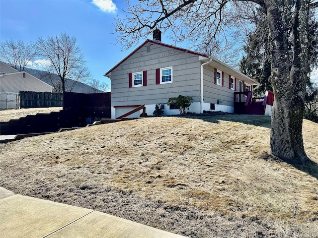 view of side of home featuring fence and a chimney