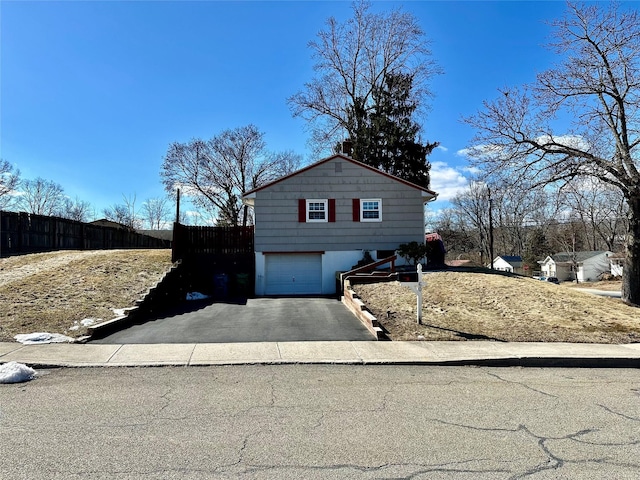 view of front of house featuring an attached garage, fence, and aphalt driveway