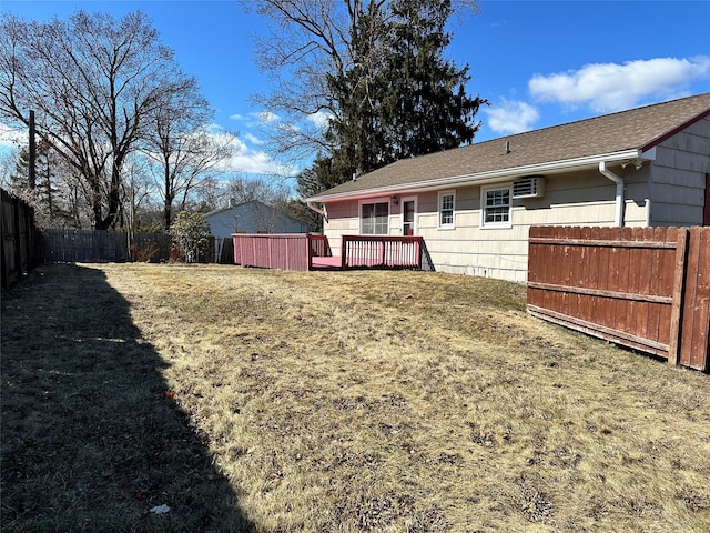 rear view of house with a fenced backyard, a deck, a lawn, and a wall mounted air conditioner