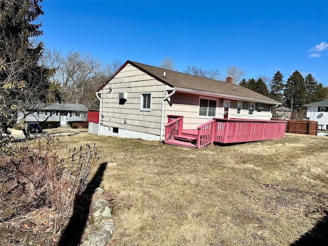 view of front of home featuring a deck, a chimney, a front yard, and fence