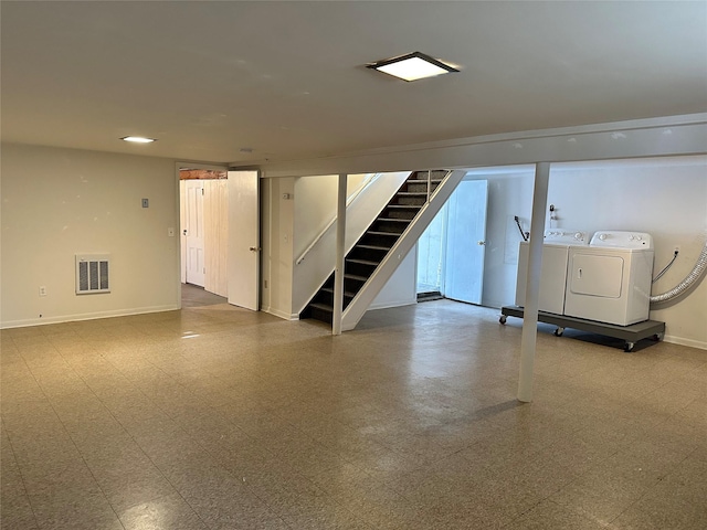 finished below grade area with visible vents, baseboards, washer and clothes dryer, tile patterned floors, and stairs