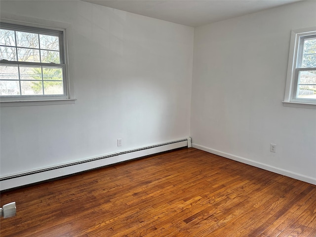 spare room with baseboards, baseboard heating, and hardwood / wood-style floors