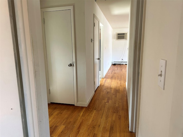 hallway with a wall mounted AC, a baseboard radiator, and wood finished floors