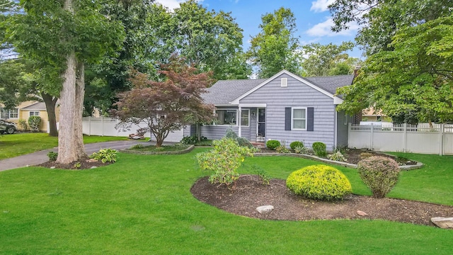 view of front of home featuring an attached garage, driveway, a front yard, and fence