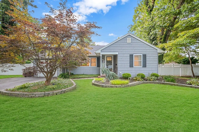 view of front facade featuring aphalt driveway, a front lawn, fence, and a garage