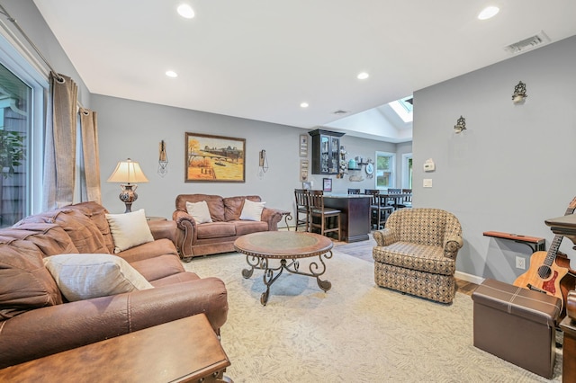 living room featuring baseboards, a skylight, visible vents, and recessed lighting