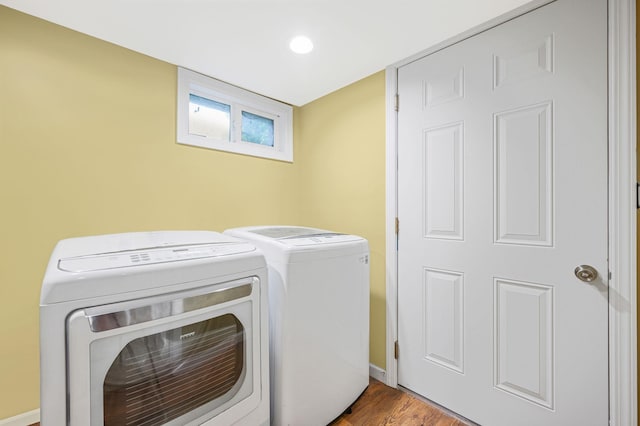 clothes washing area featuring washer and dryer, laundry area, baseboards, and wood finished floors