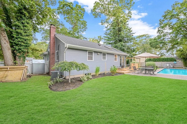 back of house with a lawn, a chimney, fence, and a fenced in pool