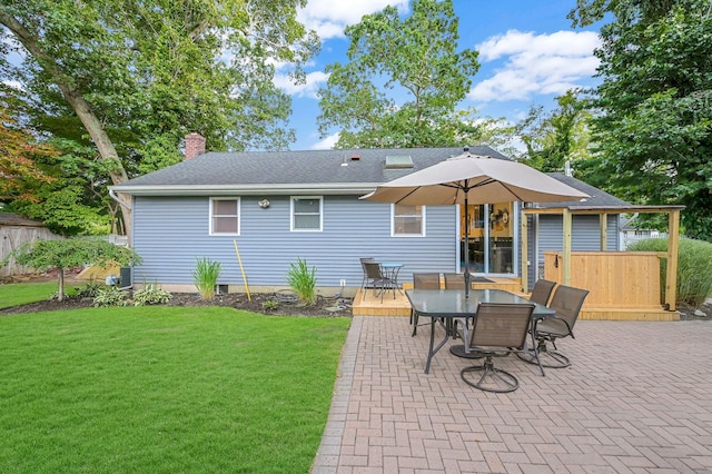 rear view of property with a chimney, a shingled roof, a lawn, outdoor dining space, and a patio area