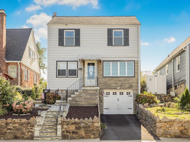 16 Joan Dr, Yonkers, NY 10704 - traditional-style house with an attached garage, asphalt driveway, and stone siding