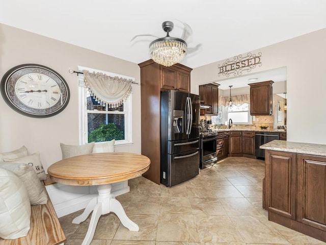 16 Joan Dr, Yonkers, NY 10704 - kitchen with stainless steel appliances, a chandelier, decorative light fixtures, tasteful backsplash, and light stone countertops