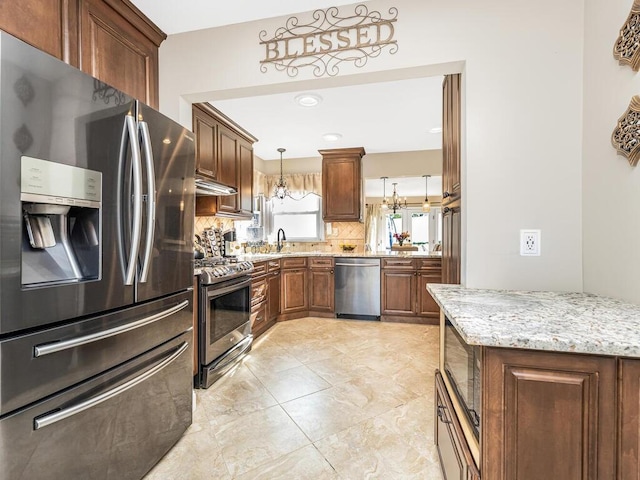 16 Joan Dr, Yonkers, NY 10704 - kitchen featuring appliances with stainless steel finishes, decorative backsplash, exhaust hood, light stone counters, and decorative light fixtures