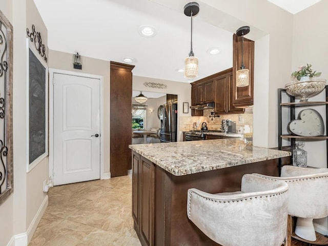 16 Joan Dr, Yonkers, NY 10704 - kitchen featuring stainless steel appliances, under cabinet range hood, a peninsula, light stone counters, and backsplash