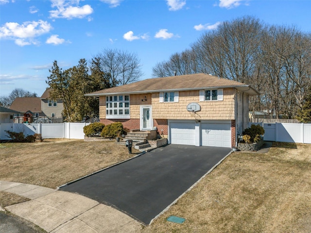 raised ranch featuring aphalt driveway, a front lawn, fence, and a gate