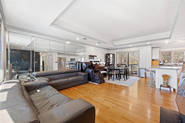 living area featuring a tray ceiling, light wood finished floors, and recessed lighting