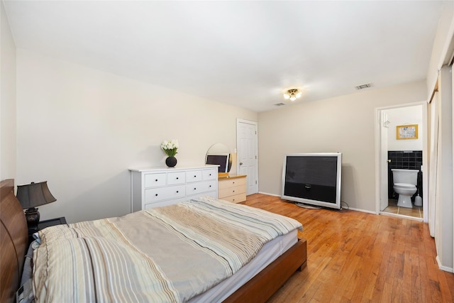 bedroom with light wood finished floors, visible vents, and baseboards