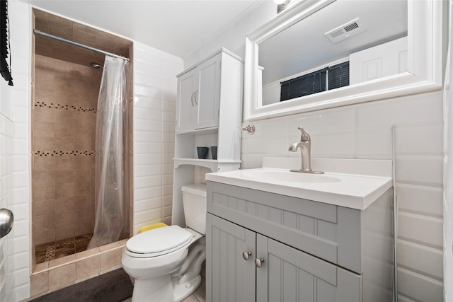 bathroom featuring toilet, visible vents, vanity, tile walls, and a shower stall