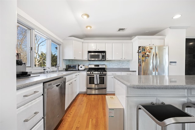 kitchen with stainless steel appliances, a sink, visible vents, and white cabinetry