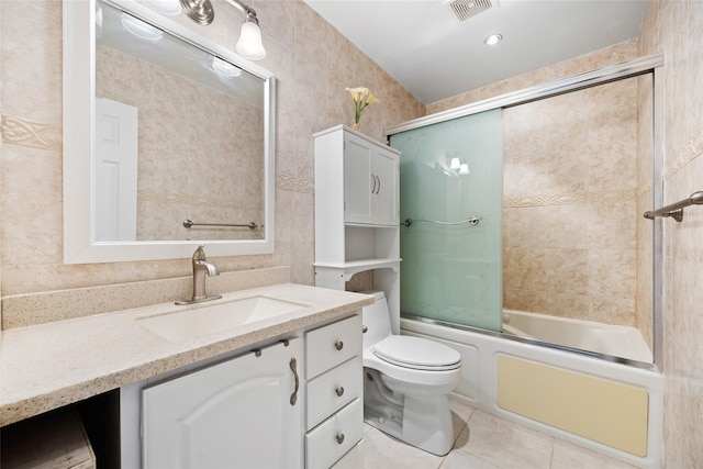 bathroom featuring bath / shower combo with glass door, visible vents, toilet, vanity, and tile patterned floors