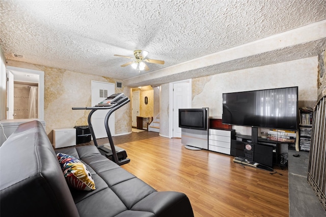 living room featuring a textured ceiling, ceiling fan, stairs, and wood finished floors