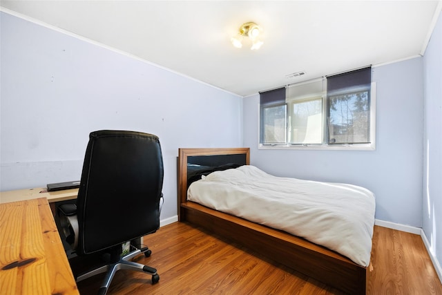 bedroom featuring visible vents, baseboards, and wood finished floors