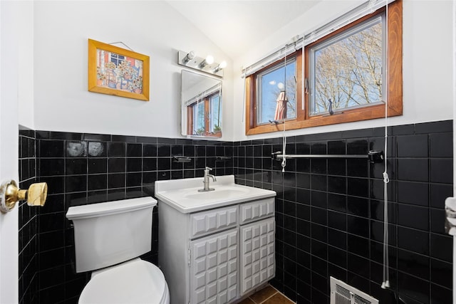 bathroom with toilet, visible vents, tile walls, and lofted ceiling