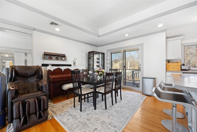 dining area with recessed lighting, visible vents, light wood-style floors, a tray ceiling, and crown molding