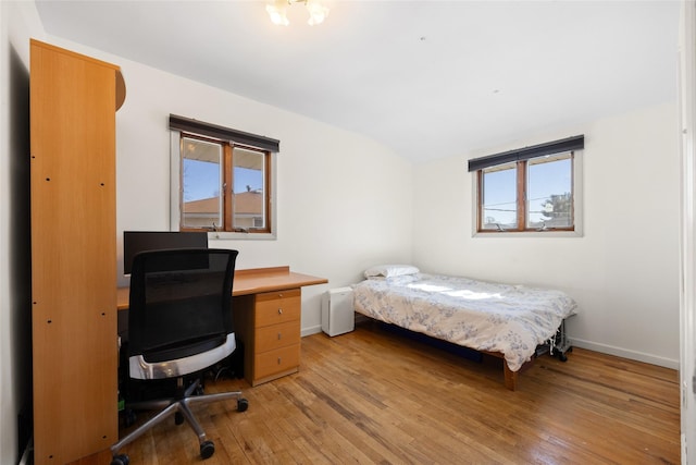 bedroom with light wood-type flooring, baseboards, and lofted ceiling