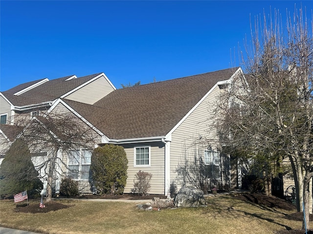 view of front facade with a front lawn and a shingled roof