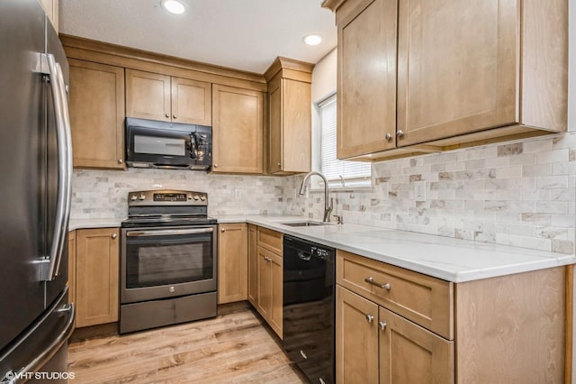 kitchen featuring decorative backsplash, light wood-type flooring, black appliances, a sink, and recessed lighting