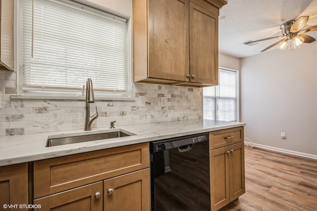 kitchen with light wood finished floors, decorative backsplash, a sink, dishwasher, and baseboards