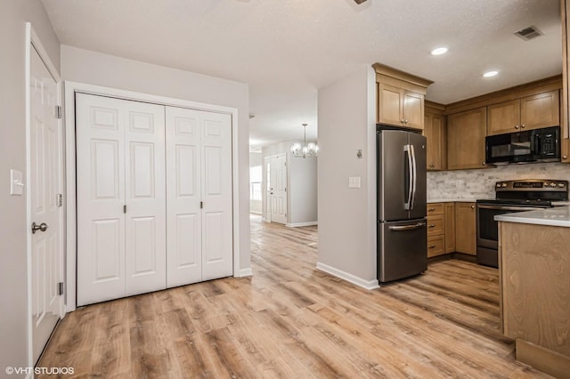 kitchen with stainless steel appliances, light countertops, visible vents, backsplash, and light wood-style flooring