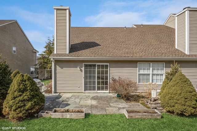 back of house with a shingled roof, a chimney, and a patio