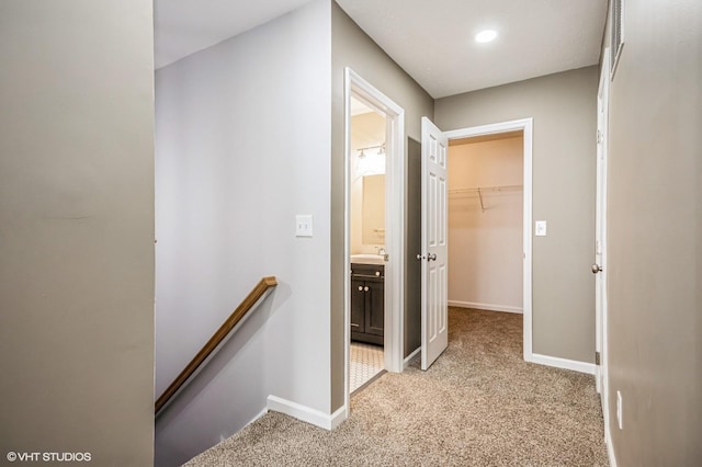 corridor with baseboards, light colored carpet, and an upstairs landing