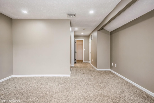 spare room featuring recessed lighting, visible vents, light carpet, a textured ceiling, and baseboards