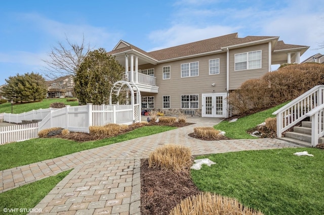 back of property with a yard, french doors, and fence