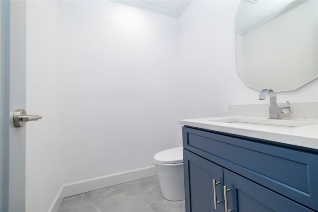 bathroom with toilet, crown molding, vanity, and baseboards