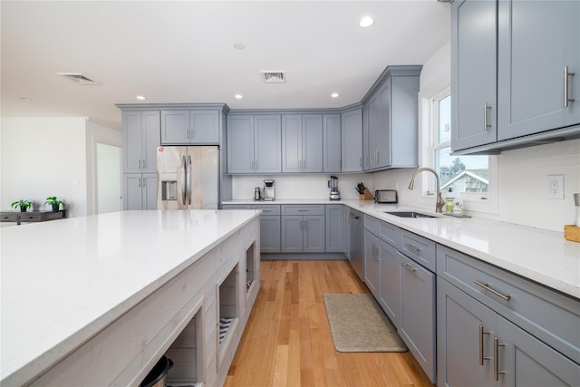 kitchen with light countertops, stainless steel appliances, a sink, and gray cabinetry