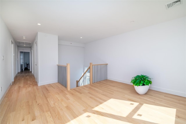 unfurnished room with attic access, visible vents, baseboards, light wood-style floors, and recessed lighting