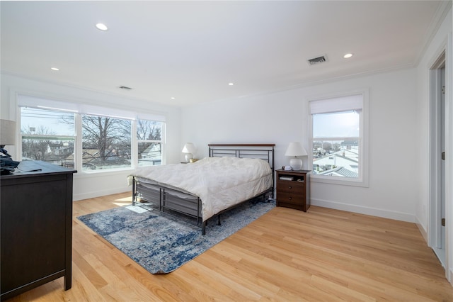 bedroom with recessed lighting, visible vents, baseboards, light wood finished floors, and crown molding