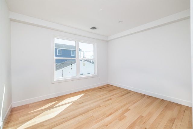 unfurnished room featuring wood finished floors, visible vents, and baseboards