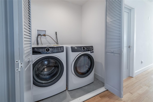 clothes washing area with light wood-type flooring, laundry area, baseboards, and washing machine and clothes dryer