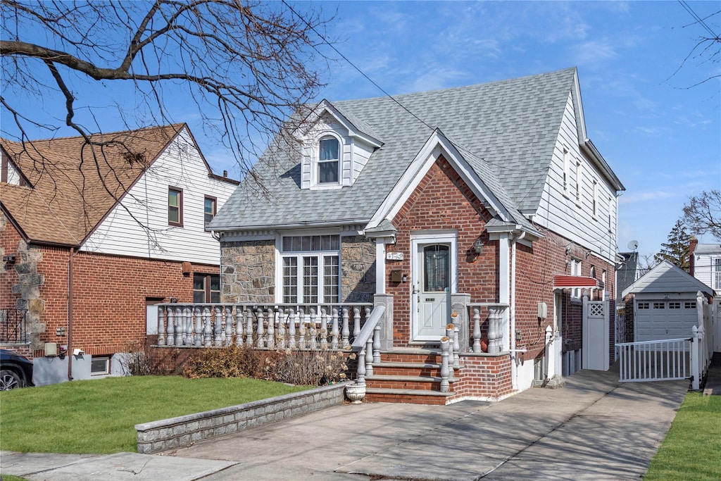 47-43 192nd St, Flushing, NY 11358 - view of front of house with a shingled roof, brick siding, driveway, and a front lawn