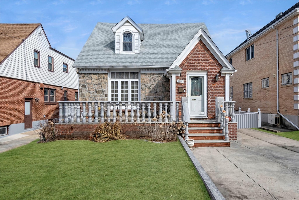 47-43 192nd St, Flushing, NY 11358 - view of front of house featuring central AC unit, covered porch, stone siding, roof with shingles, and a front yard