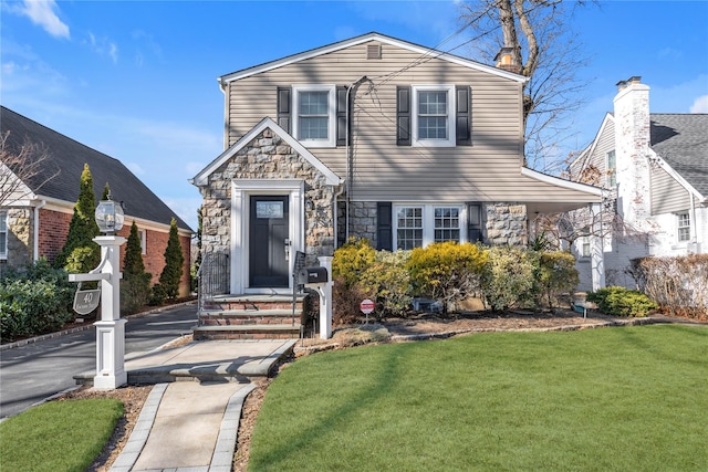 traditional home featuring stone siding and a front lawn