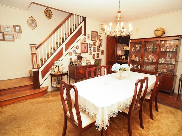 carpeted dining space with a chandelier and stairs