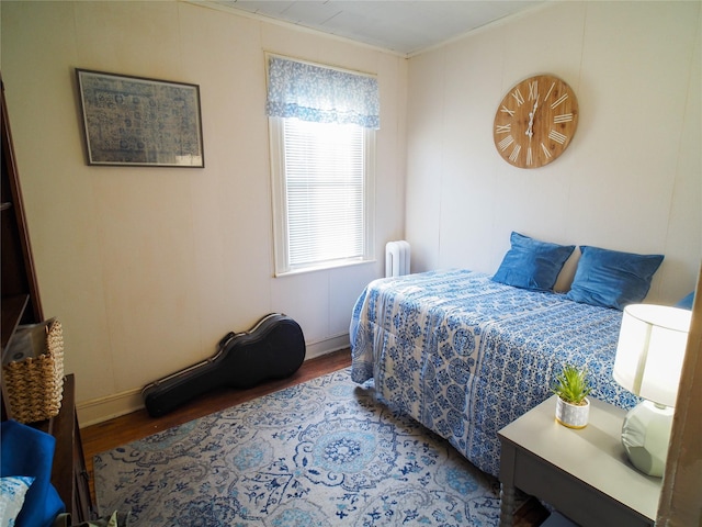 bedroom with radiator heating unit, crown molding, and wood finished floors