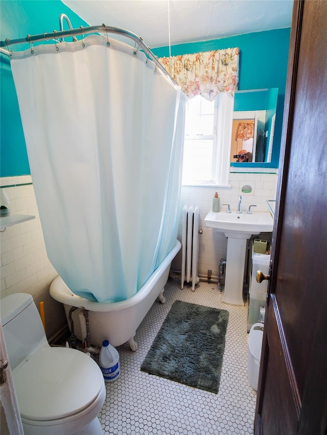 bathroom with wainscoting, toilet, radiator heating unit, tile patterned floors, and tile walls