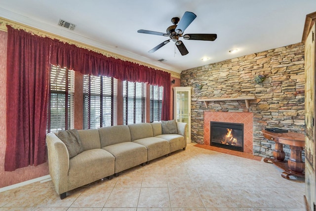 living room featuring light tile patterned floors, visible vents, ceiling fan, a stone fireplace, and baseboards